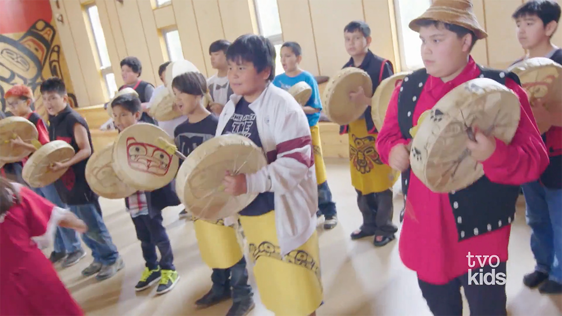 A group of children are drumming during a Tsimshian nation ceremony.