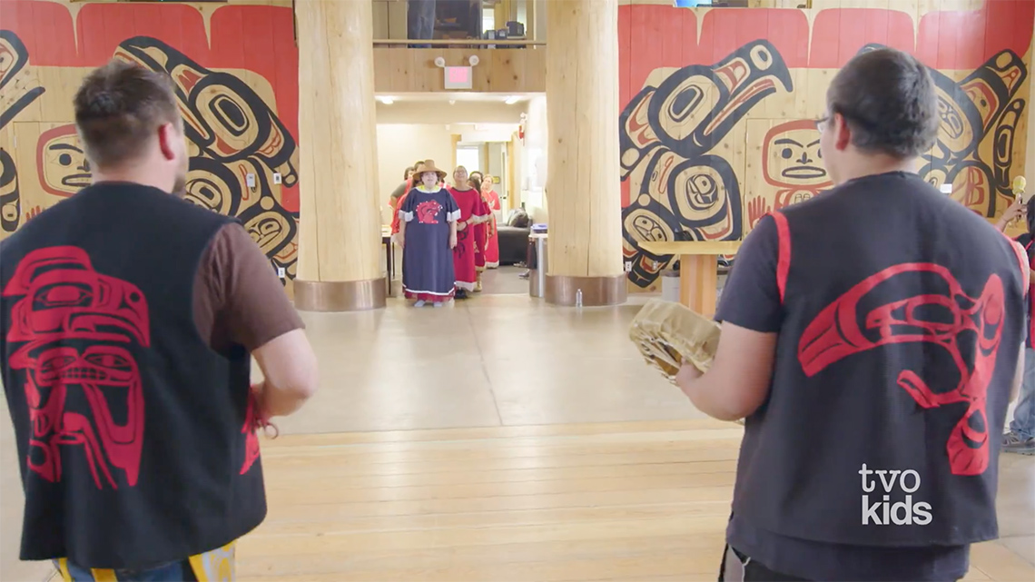 Dancers enter a large room with two drummers inside.
