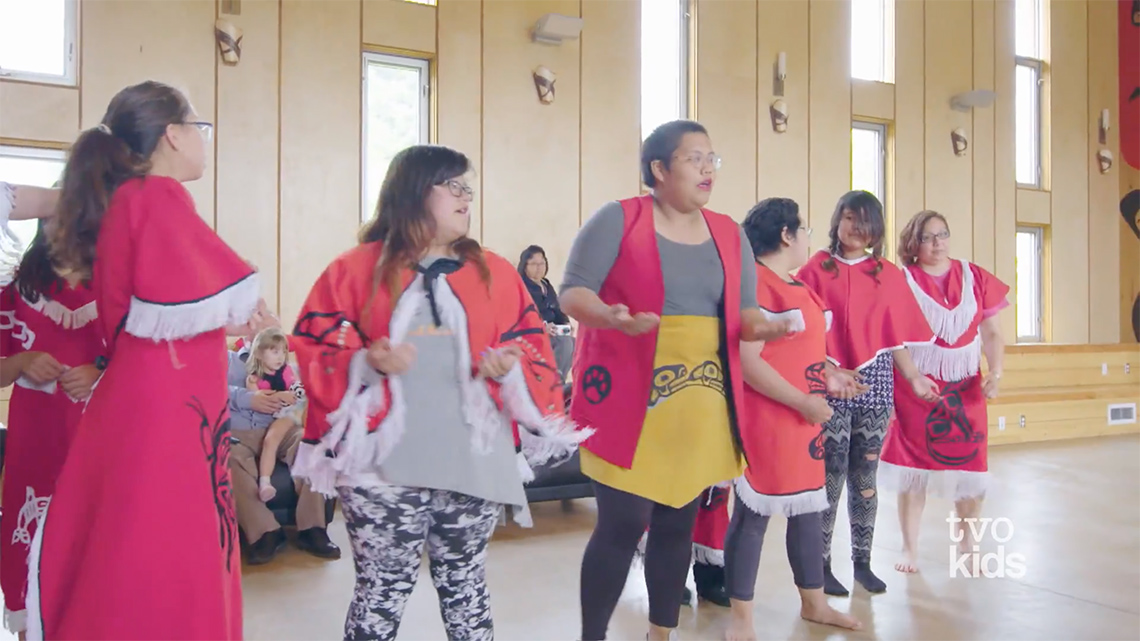 A group of dancers wearing a variety of regalia.