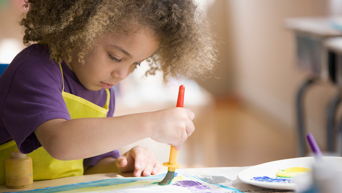 A child is painting a picture with a brush. 