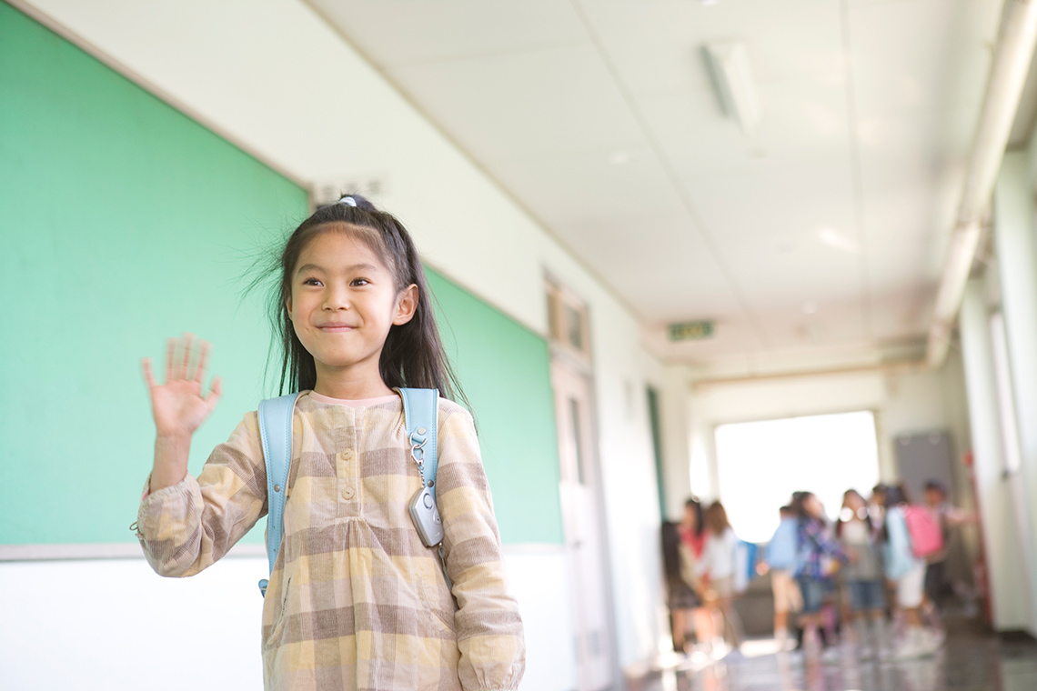 A child is smiling and waving.