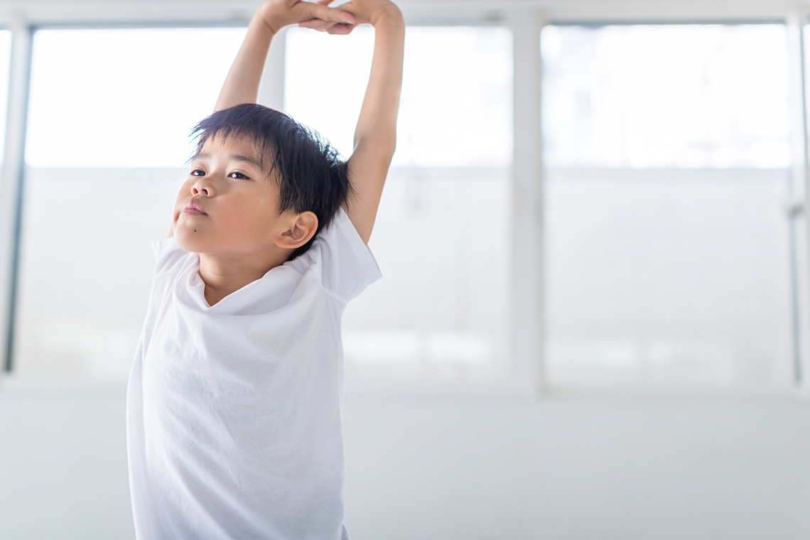 A child is stretching their arms above their head.