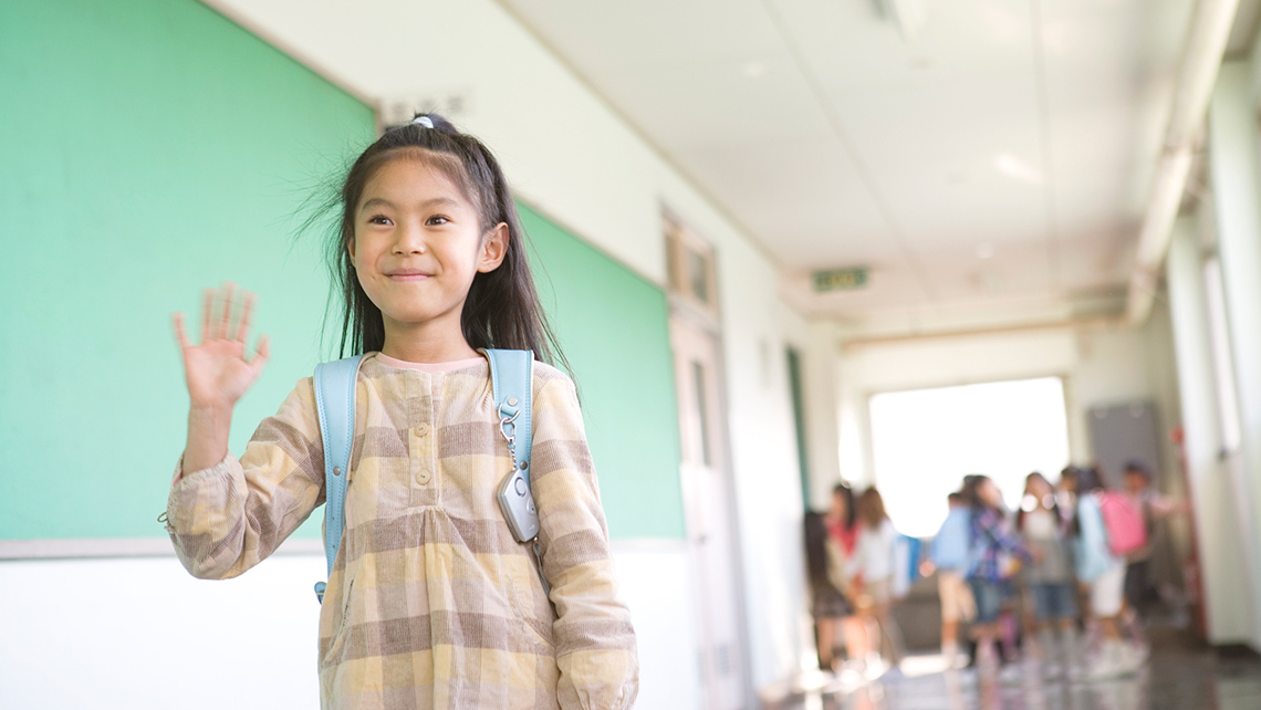 A child is smiling and waving.