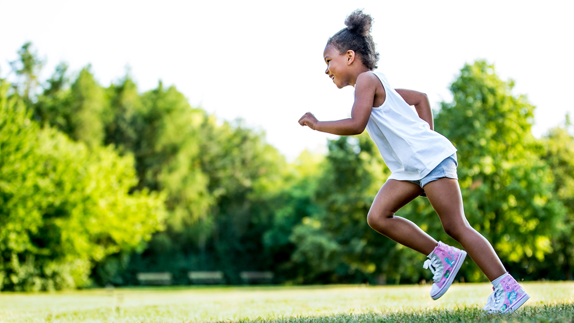 A child is running on a paved footpath.