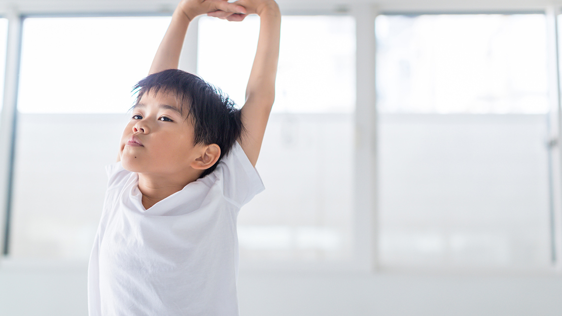 A child is stretching their arms above their head.