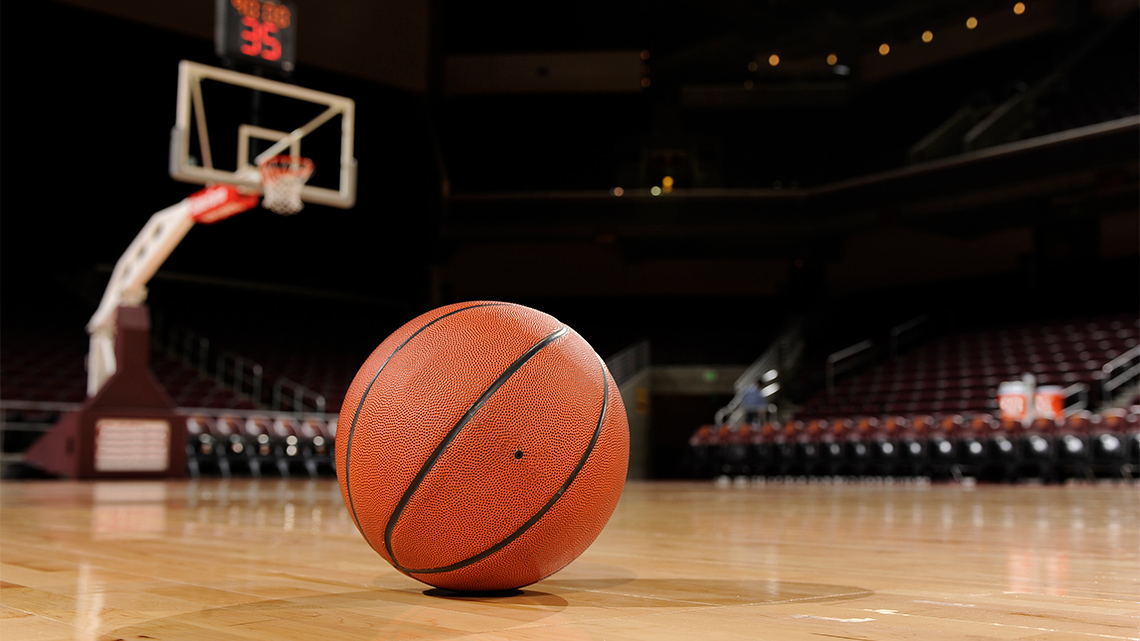 Basketball rolling on the floor of a gymnasium.