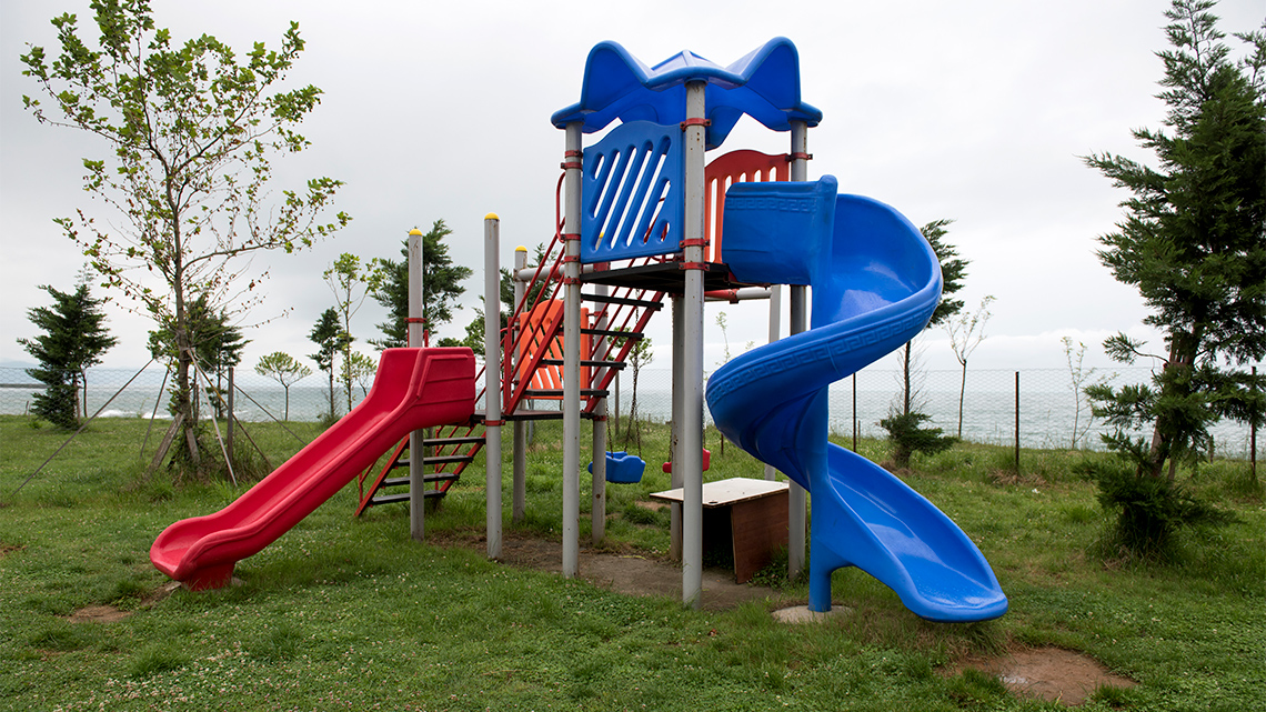 A twisted and a straight slide at a playground.