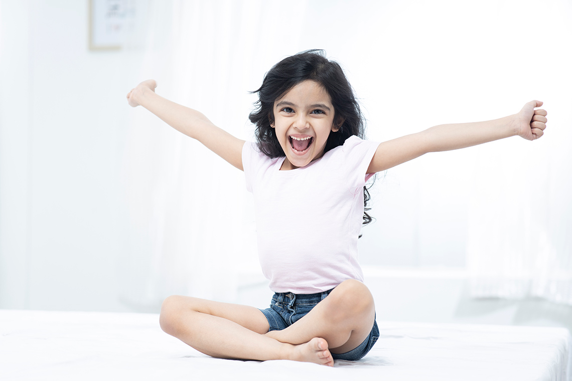 A person is sitting cross-legged with their arms outstretched.