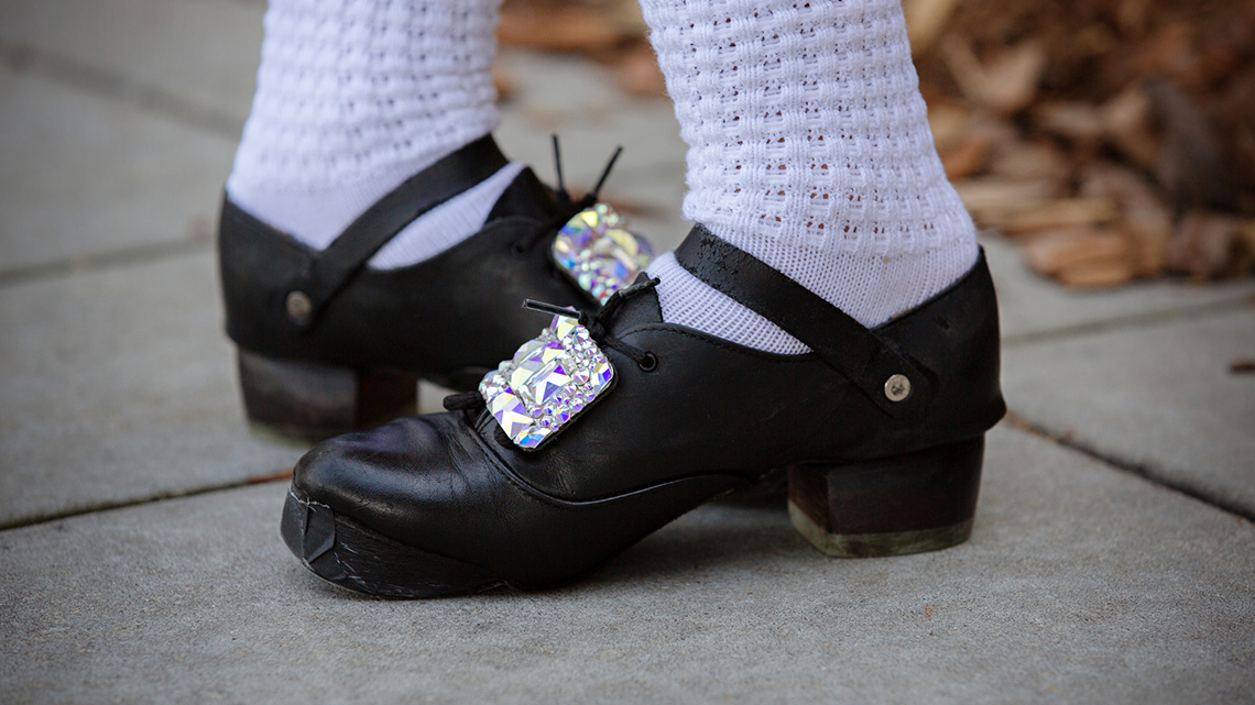 A close-up image of a dancer’s feet. The dancer is wearing traditional Irish step dancing hard shoes.