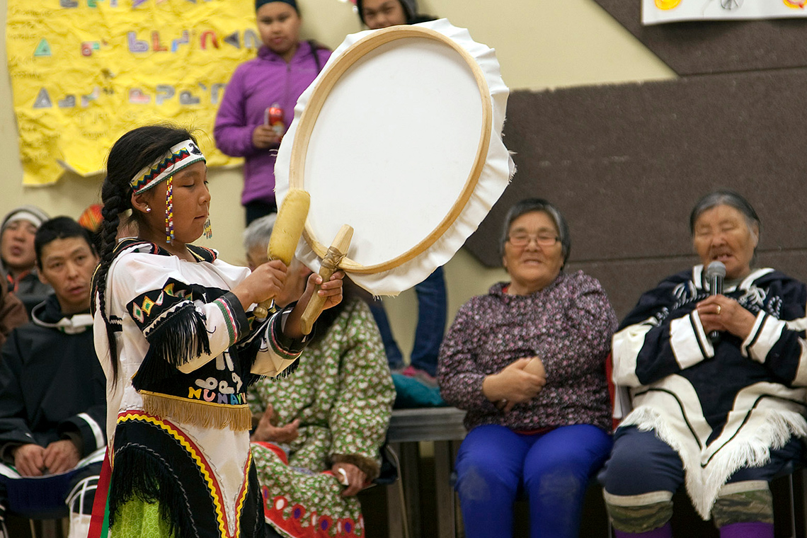 An Inuit child is performing a Drum Dance.
