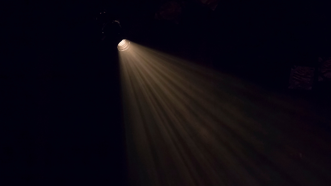 A dark stage with a single spotlight illuminated. 