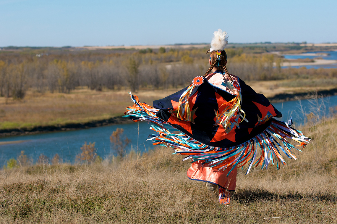 Individual wearing colourful traditional regalia and shawl for Indigenous Fancy Shawl dance.