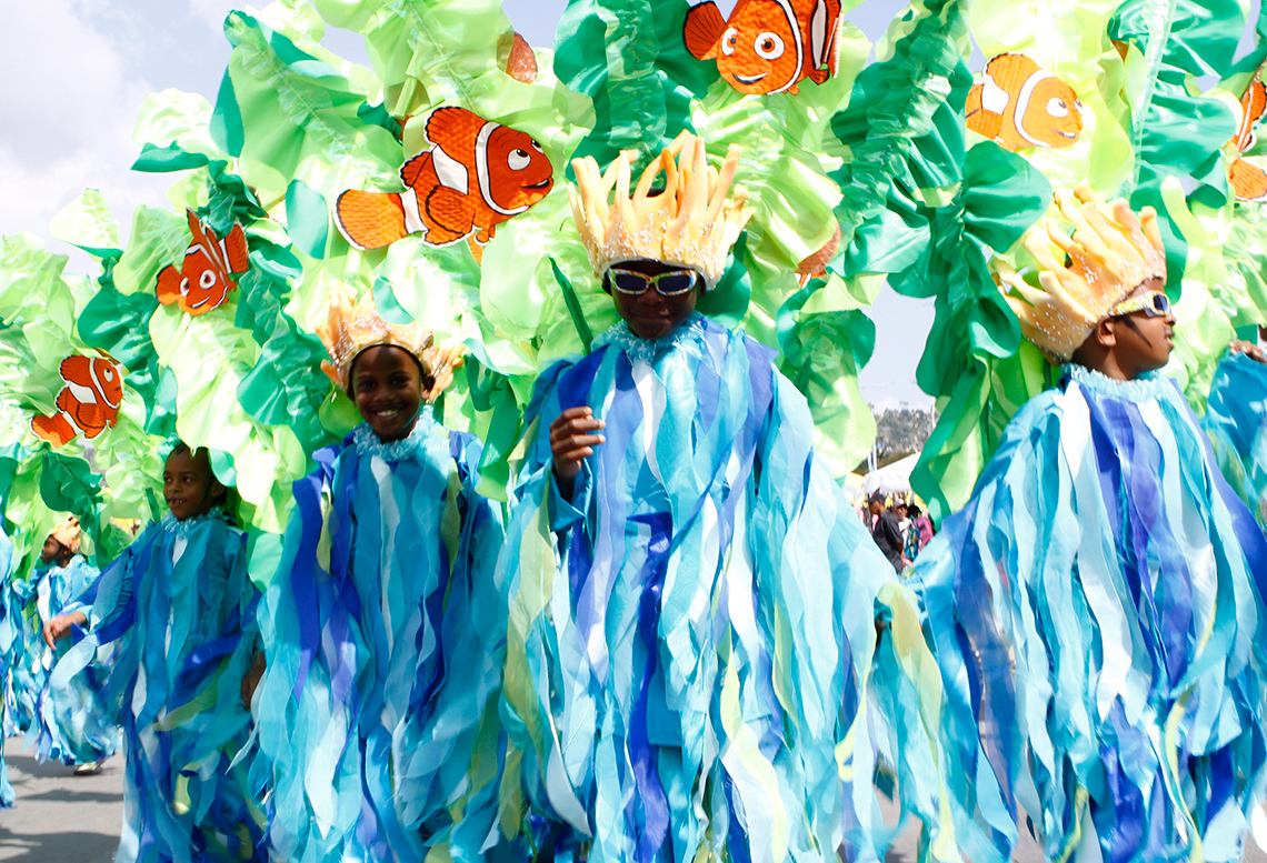 Five young people dance wearing headdresses resembling corals with fish and sea plants, and outfits made with streamers in sea colours.