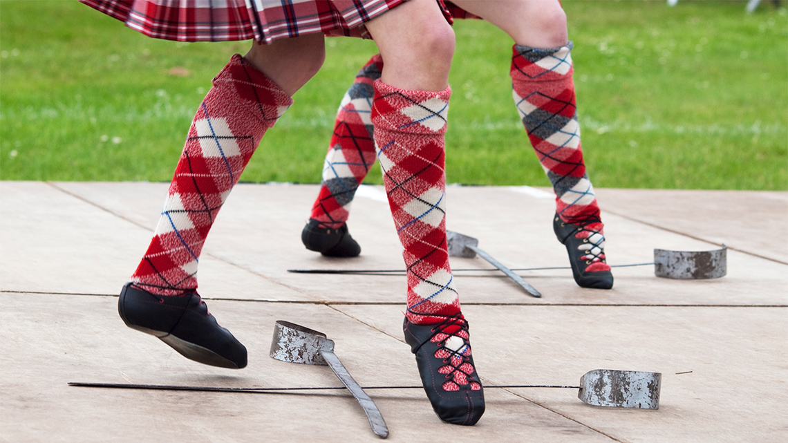 A Highland dancer dances over and across the sword.