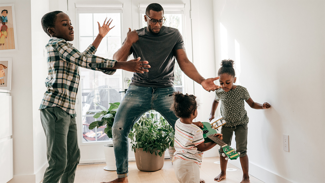 An adult is dancing with three children.