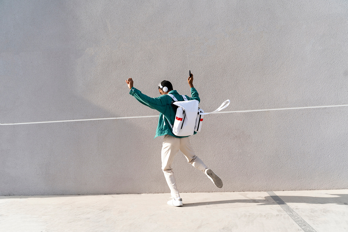 A dancer, having their back to the camera, and is dancing with both arms raised in the air