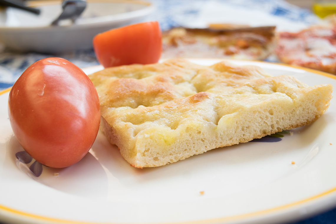 A piece of Bannock bread. There are tomatoes beside it on the plate.