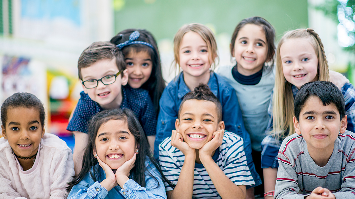 A group of children smiling and paying attention.