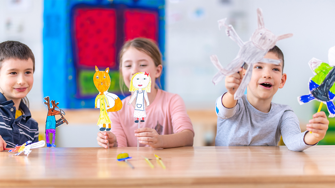 Puppet show being performed by a child with paper cut out dolls of a prince and princess.