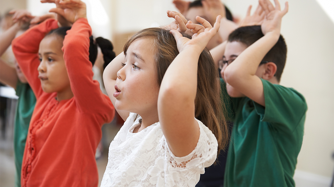 A group of students with their hands on their heads pretending to be animals with large ears or antlers.