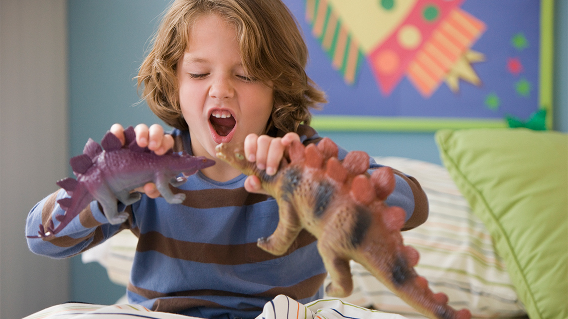 Child playing with toy dinosaurs.