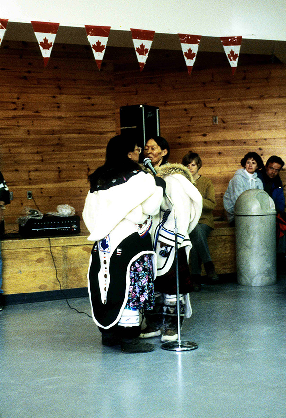 Two Inuit throat singers facing each other. One of the singers is holding a microphone between them.