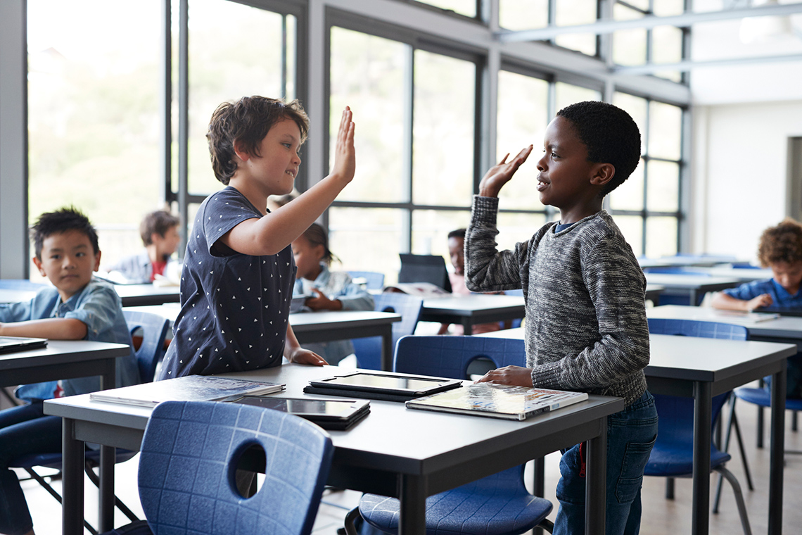Two children high fiving in class.