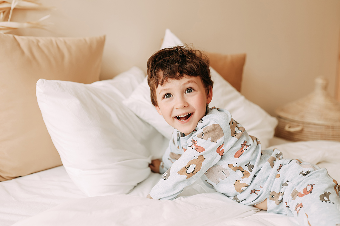 A child smiling and laying on a bed.