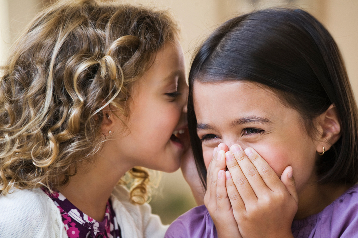 A child whispering into another child's ear.