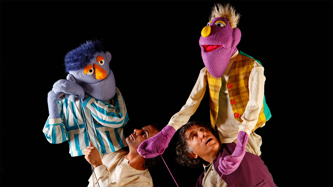 Two puppeteers holding their puppets during a show.