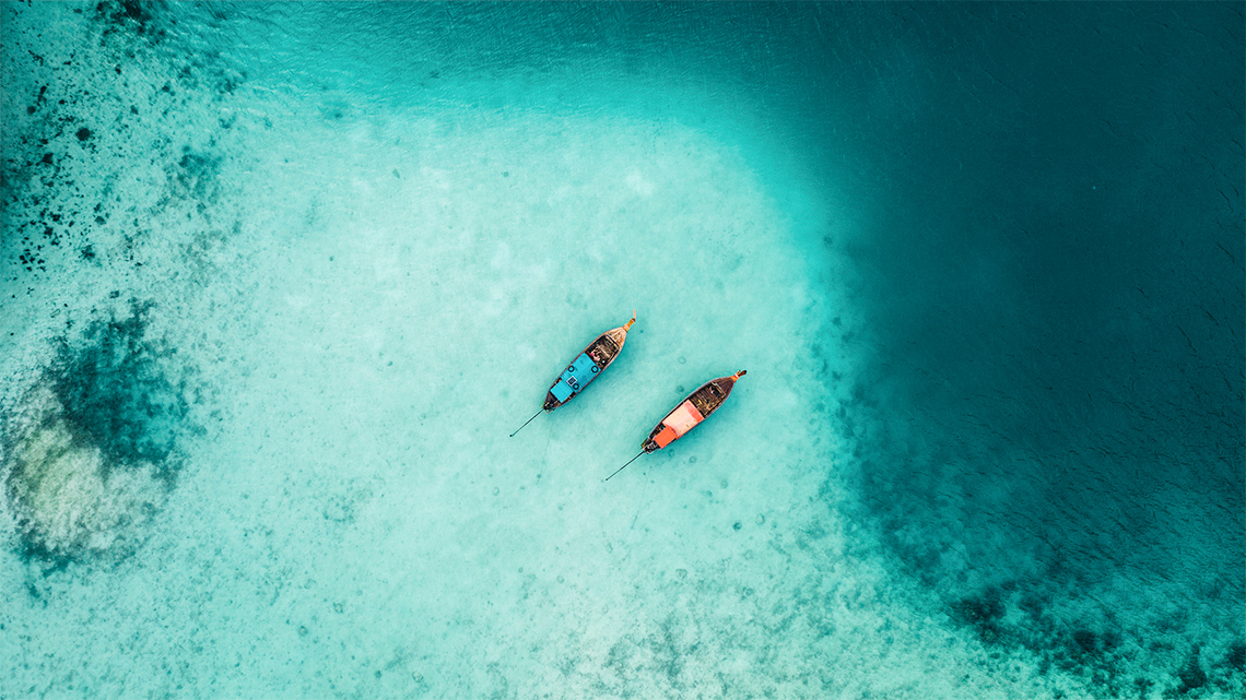 Two boats float atop clear water.