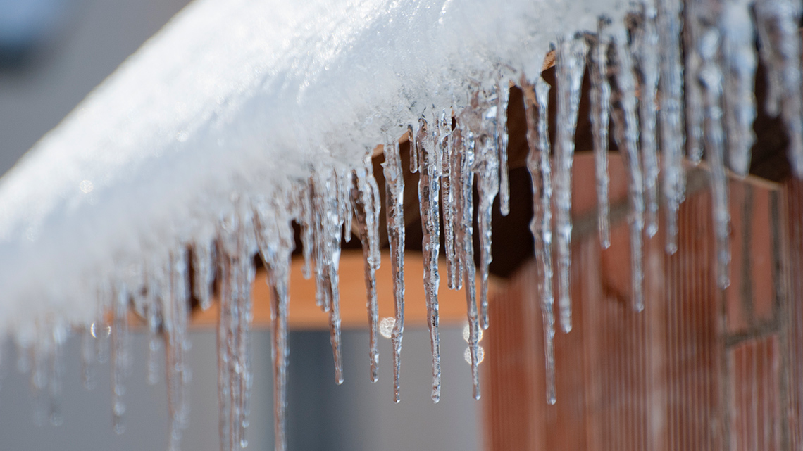 Long icicles hang off the edge of a roof.