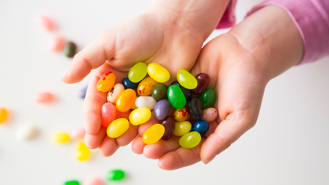 A person is holding a handful of jellybeans.