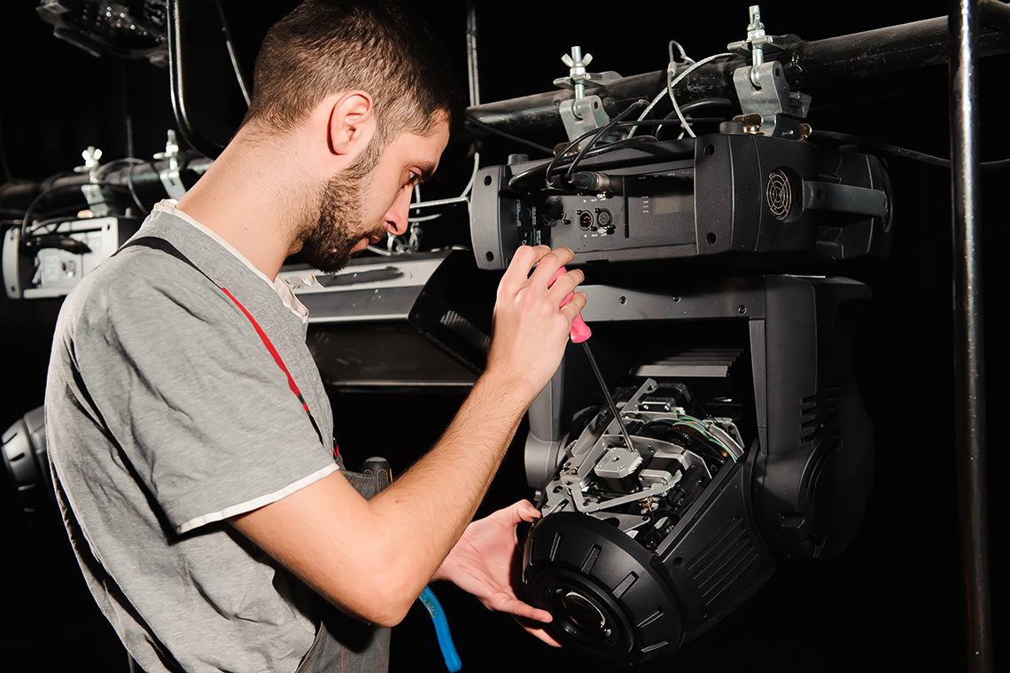 A lighting designer fixing a stage light.