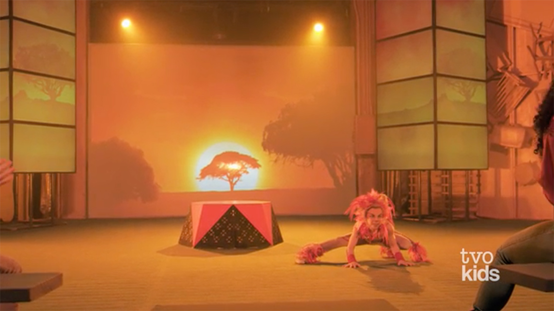 A child, dressed a lion, is crouched down and ready to pounce.