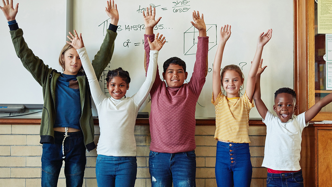 A group of children in a line. Their hands are up over their hands and swaying. 