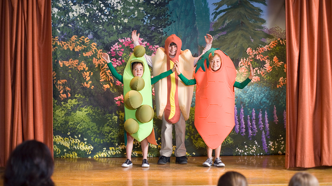 Three children on stage dressed as different types of food.