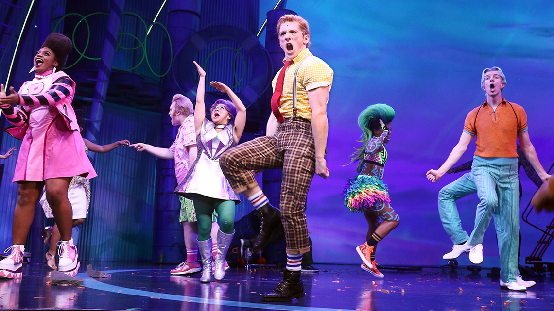 A group of actors on a stage performing a routine.