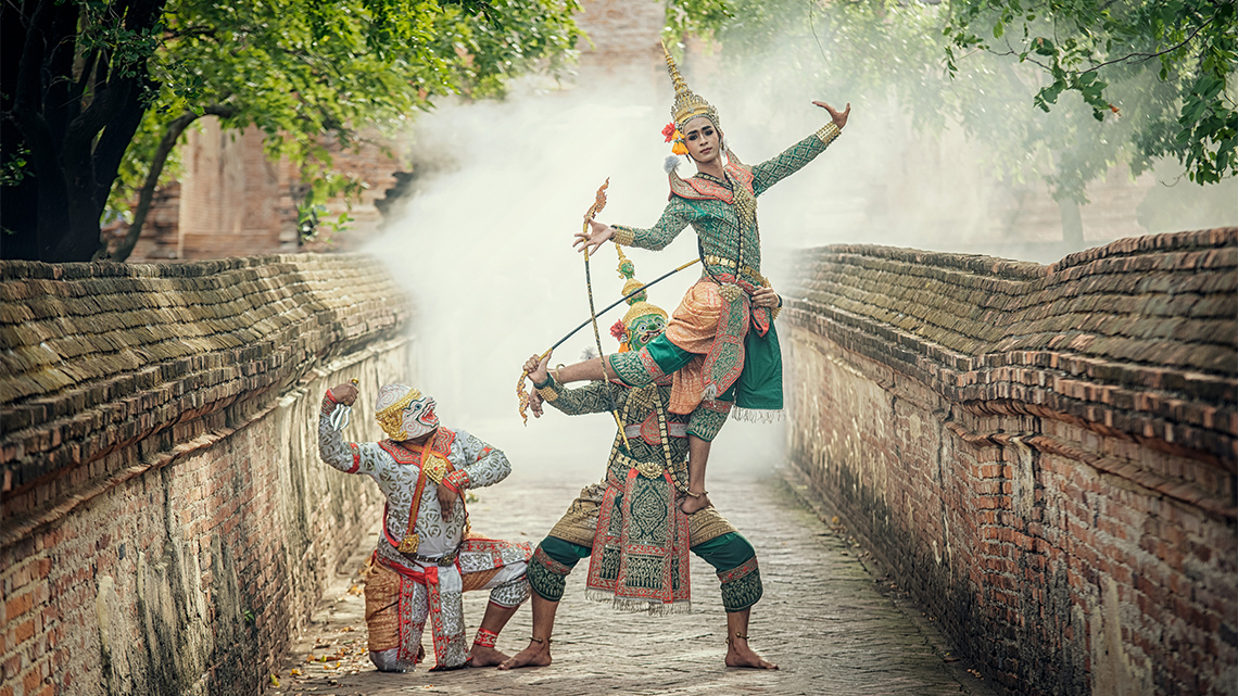 Three performers from Thailand's royal and traditional mime show, known as Khon wearing costumes and masks perform in a misty brick laneway.