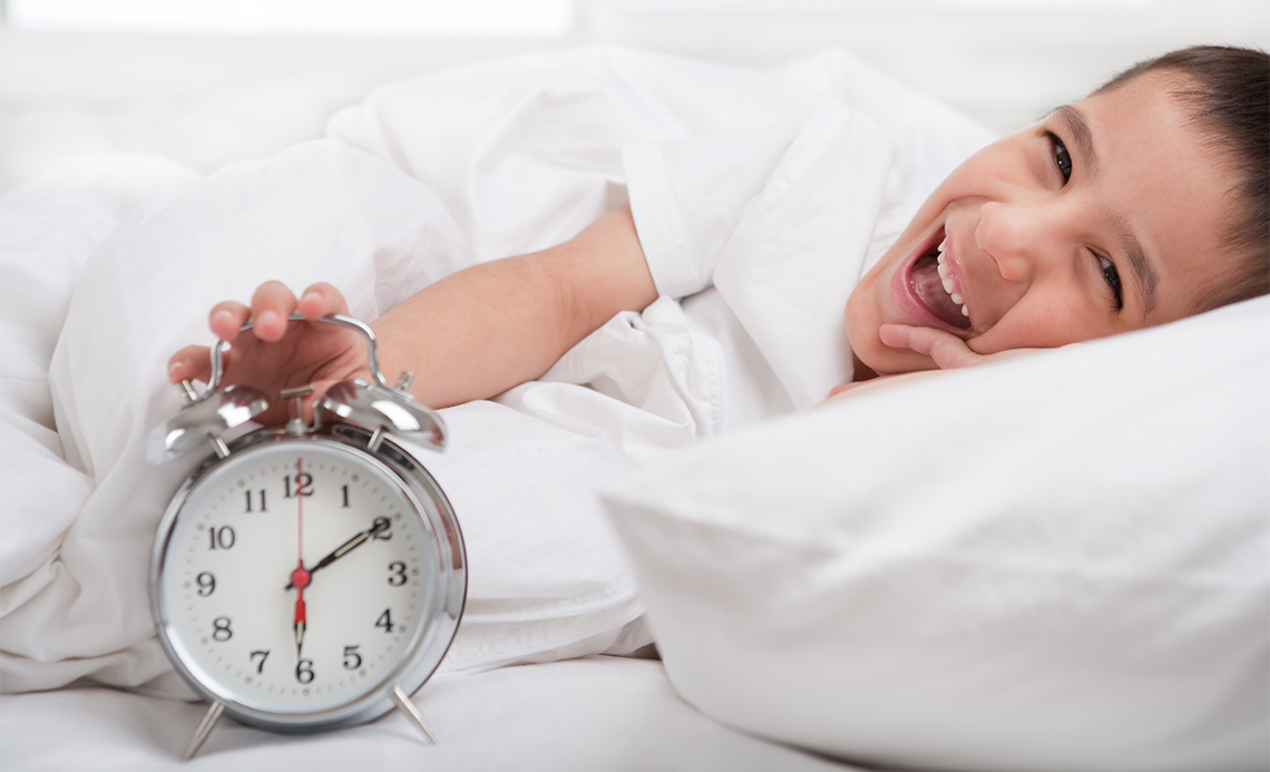  A child holding an alarm clock while laughing.