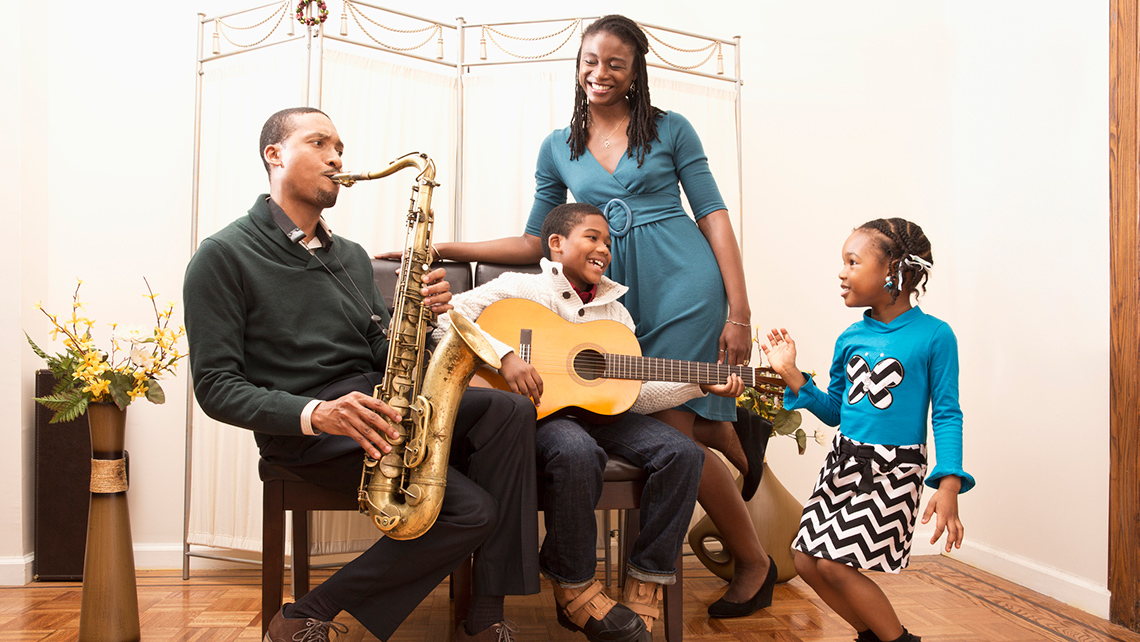 A family playing instruments together while one of the children dances.