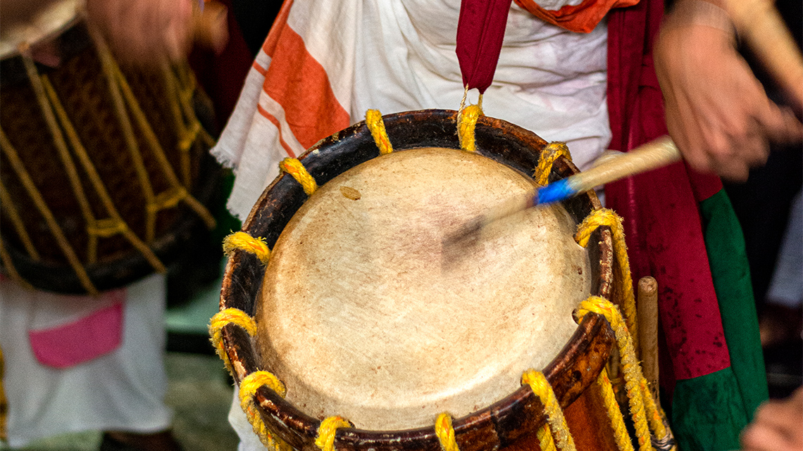 A close-up shot of a person playing the chenda.