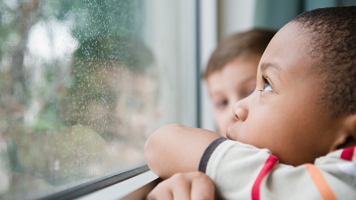 Children watching the rain through a window.