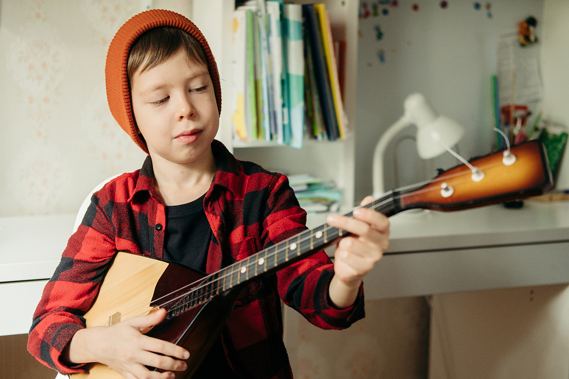 Child playing the balalaika in their room.