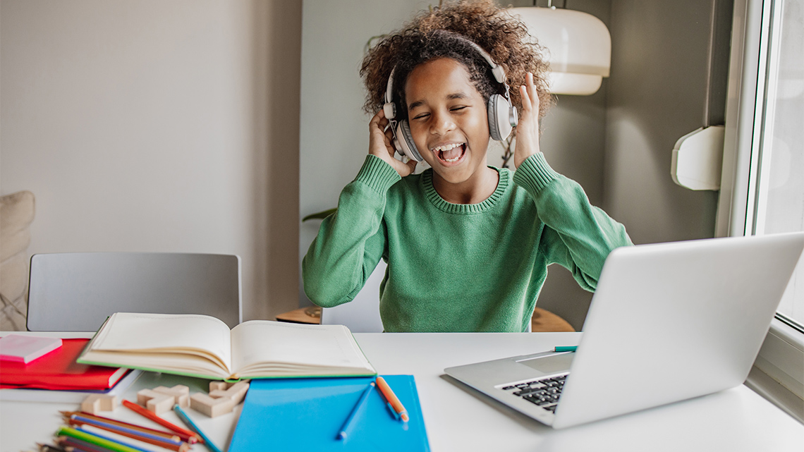 A child listening to music through their headphones and singing.
