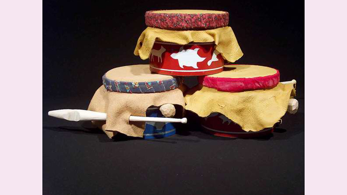 A set of water drums, with skin stretched over wooden bases and held on with a decorated edge.