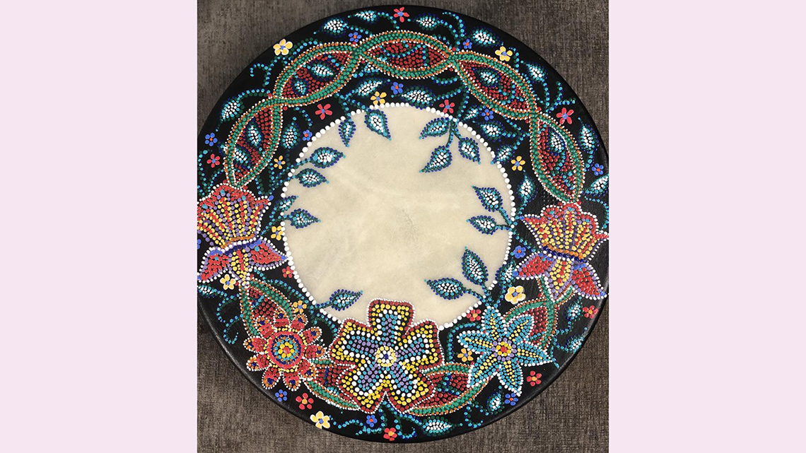A healing drum created from cowhide. Its outer edge is painted with a complex flower design.