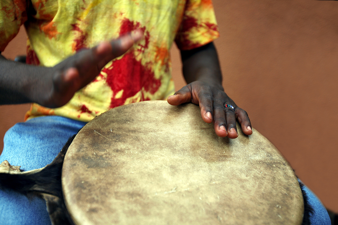 A person’s hands playing a djembe drum.