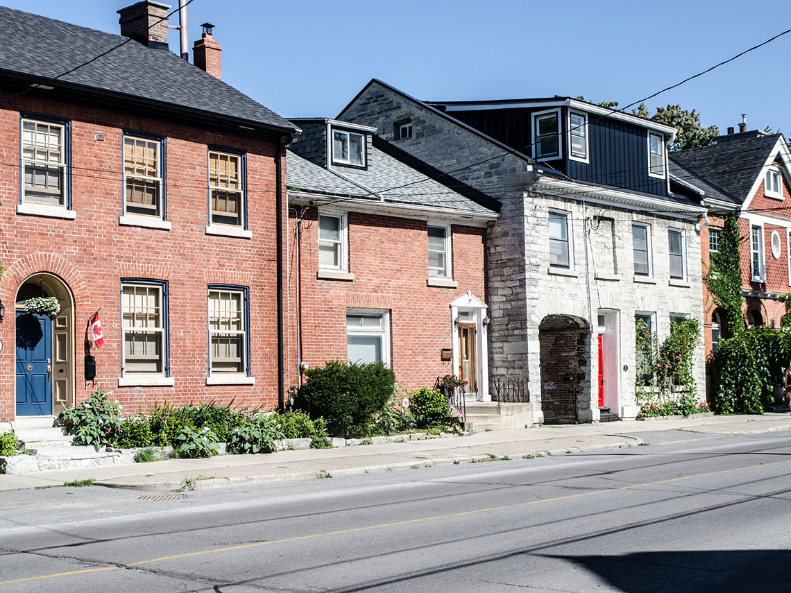 A street lined with houses. There is greenery in front of the houses.