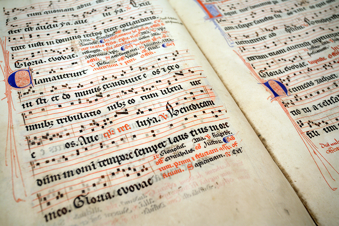 An old book with a musical staff and lyrics. There are small squares on the musical staff.
